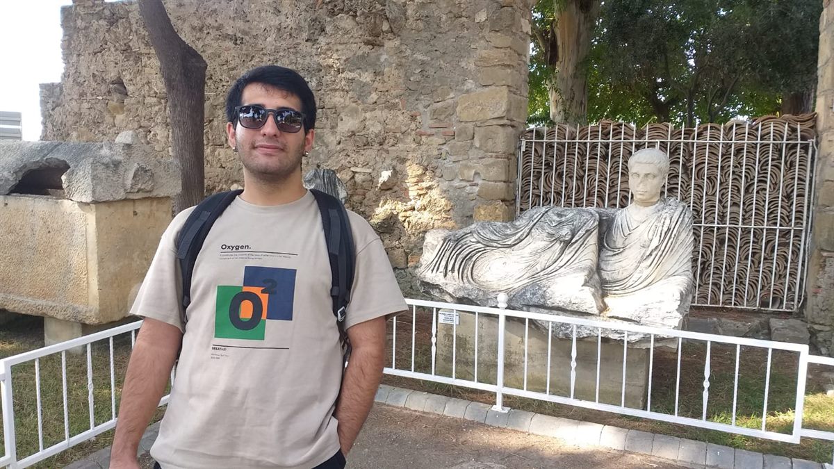 Ali ALTUNTAŞ, bir ören yerinde antik bir heykelin yanında